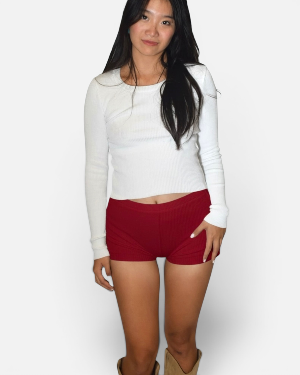 Woman wearing a white long-sleeve top and red hot pants on a white background