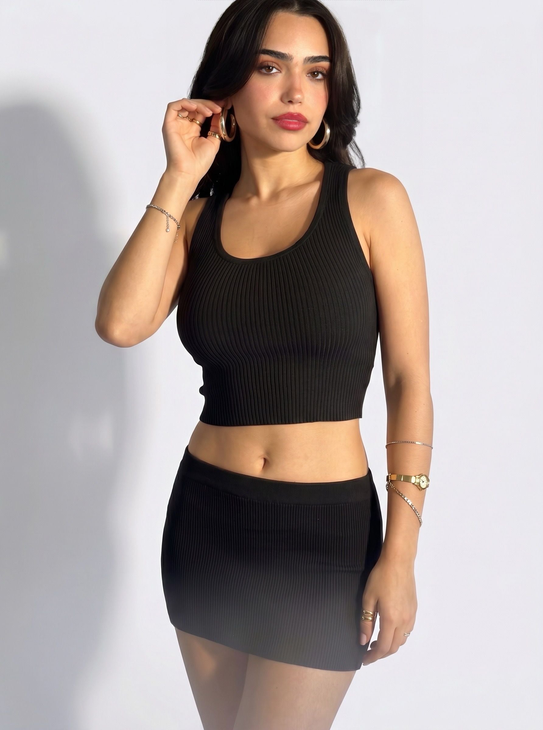 Woman wearing matching black rib knit crop scoop neck tank and mini skirt by TKHLA 