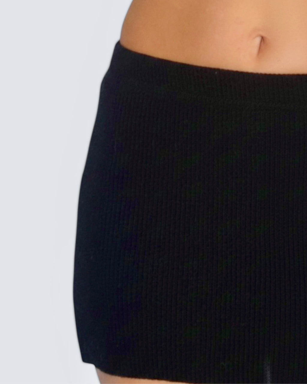 Black ribbed knit skirt on a plain background