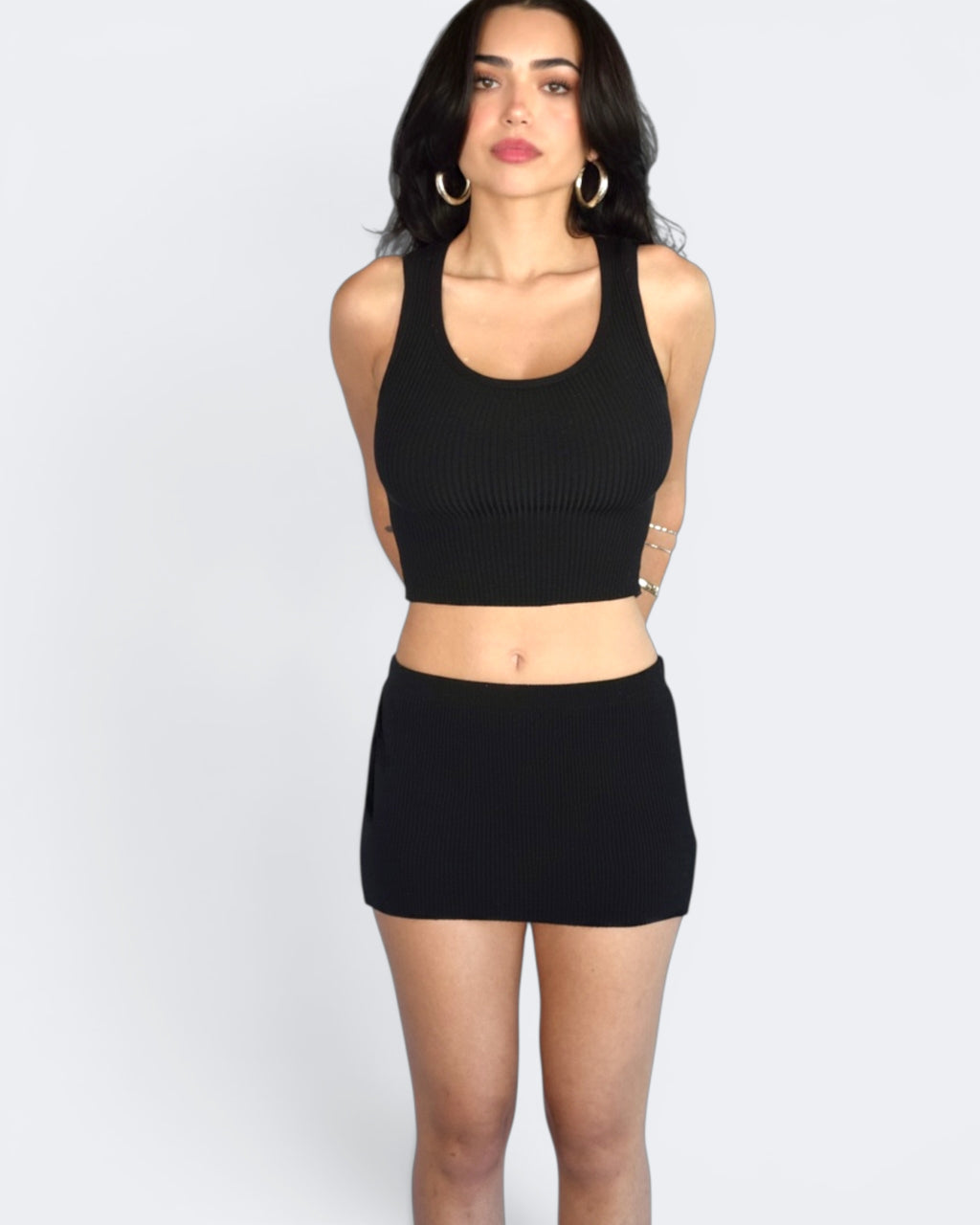 Woman wearing a black crop top and skirt set on a white background