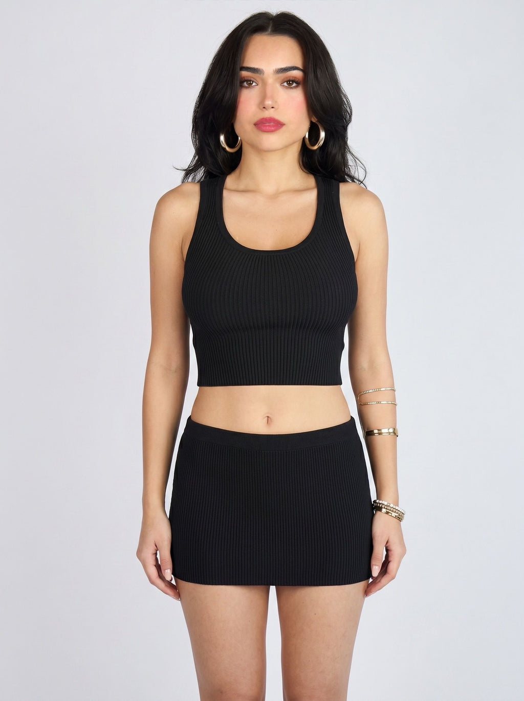 Woman wearing matching black rib knit crop scoop neck tank and mini skirt by TKHLA 