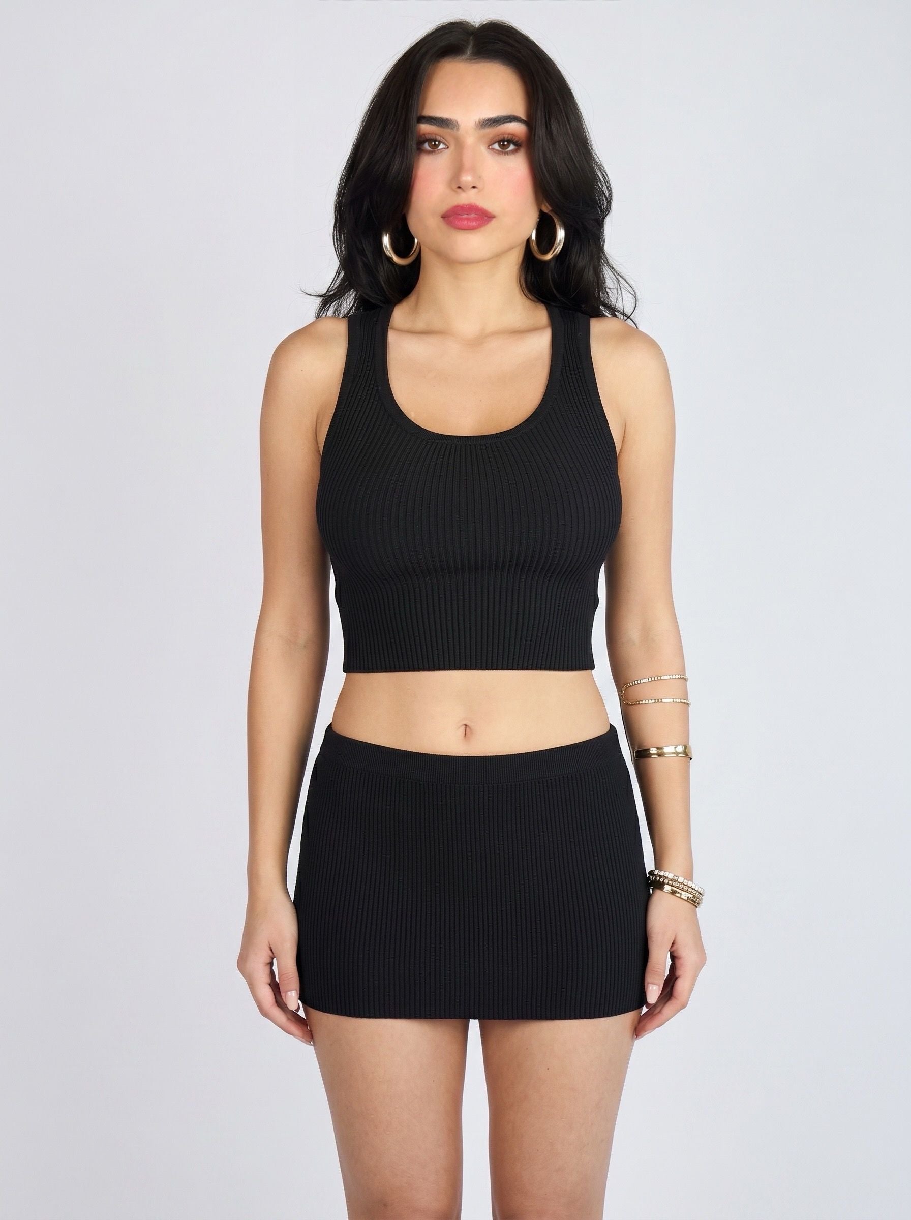 Woman wearing matching black rib knit crop scoop neck tank and mini skirt by TKHLA 
