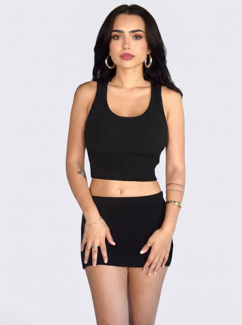 Woman wearing matching black rib knit crop scoop neck tank and mini skirt by TKHLA 