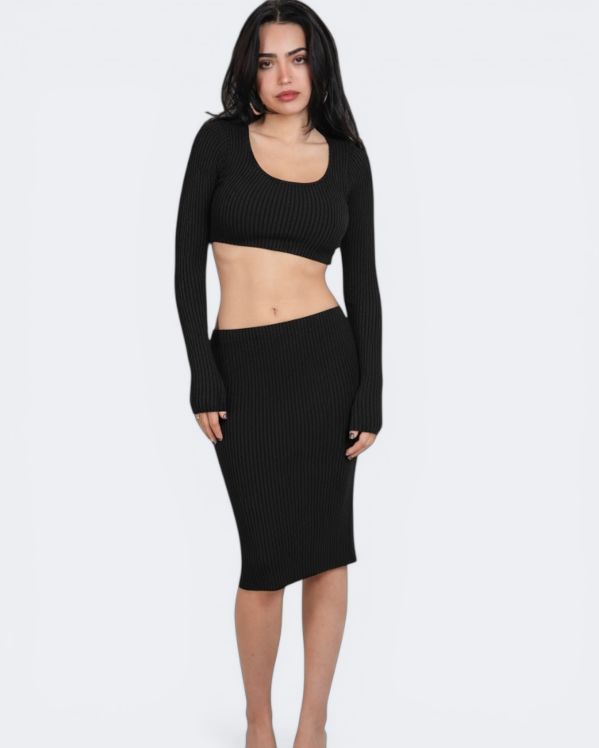 Woman wearing a black ribbed crop long-sleeve top and skirt on a white background