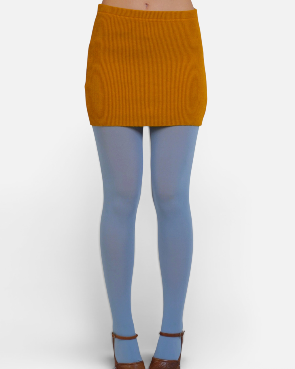 Person wearing a Dijon mustard yellow ribbed skirt and blue tights on a white background