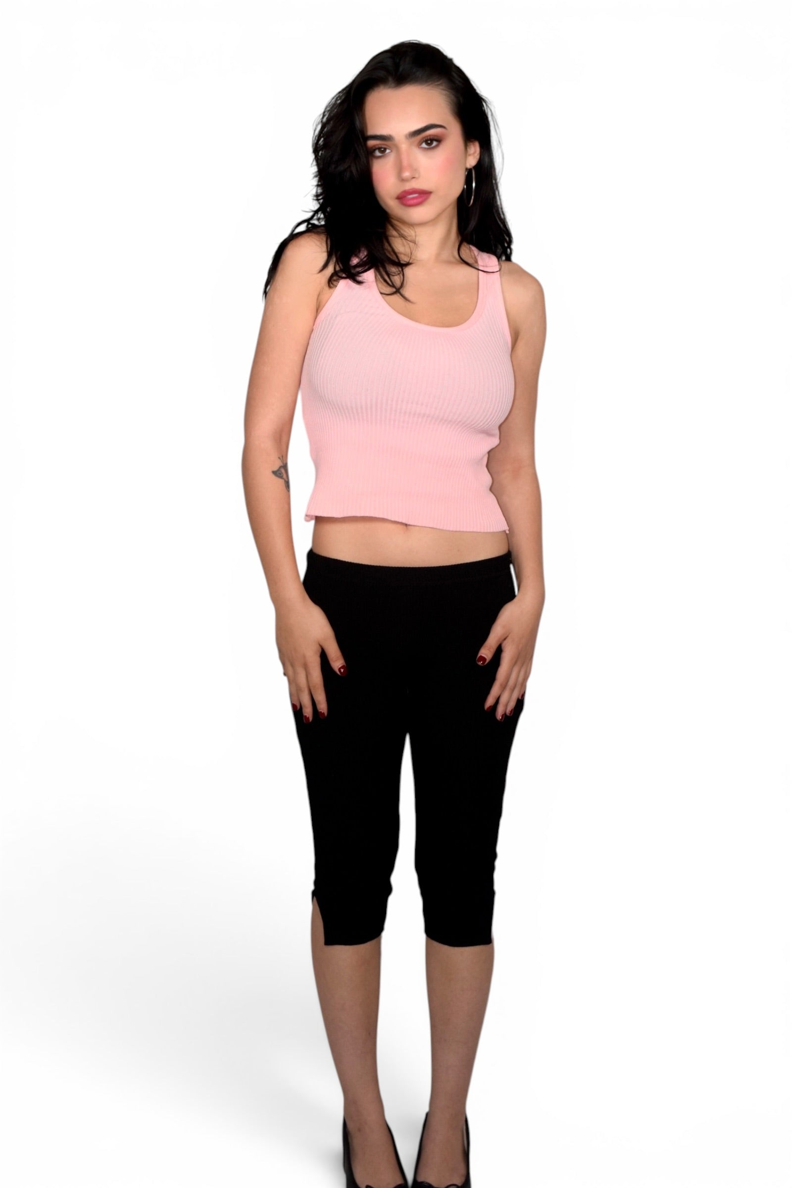 Woman wearing a pink sleeveless top and black capri pants on a white background