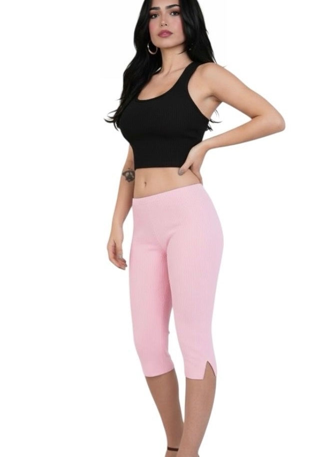 Woman wearing a black crop top and pink capri leggings on a white background