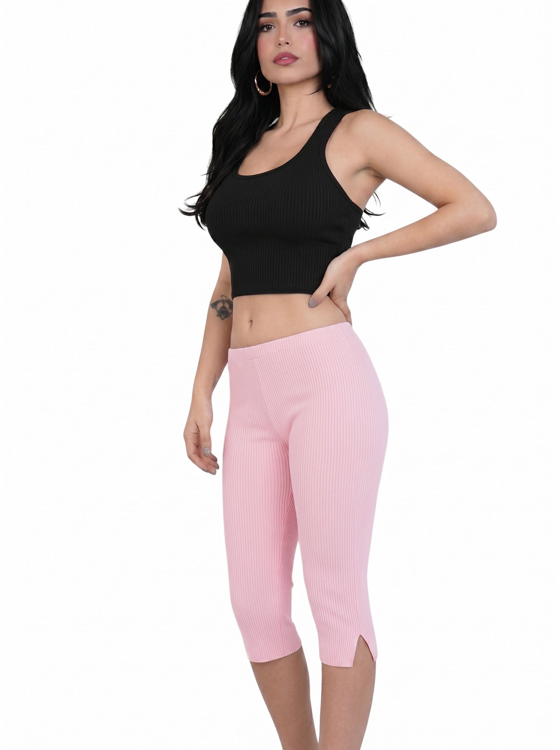 Woman wearing pink rib knit Capri pants with slit on side, paired with black crop tank. 