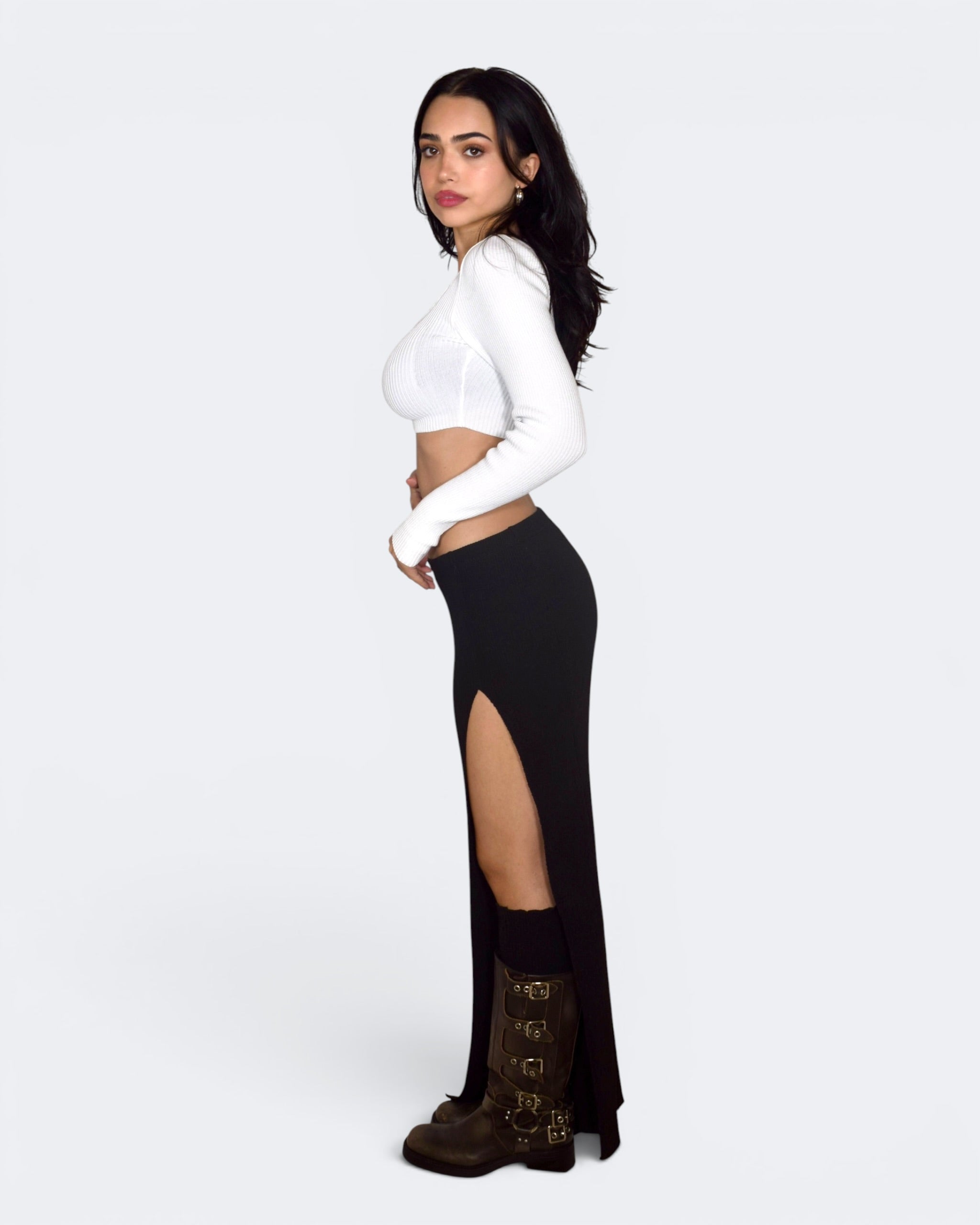 Woman wearing black long sleeve skirt with high slit, crop long sleeve white top. By TKHLA 