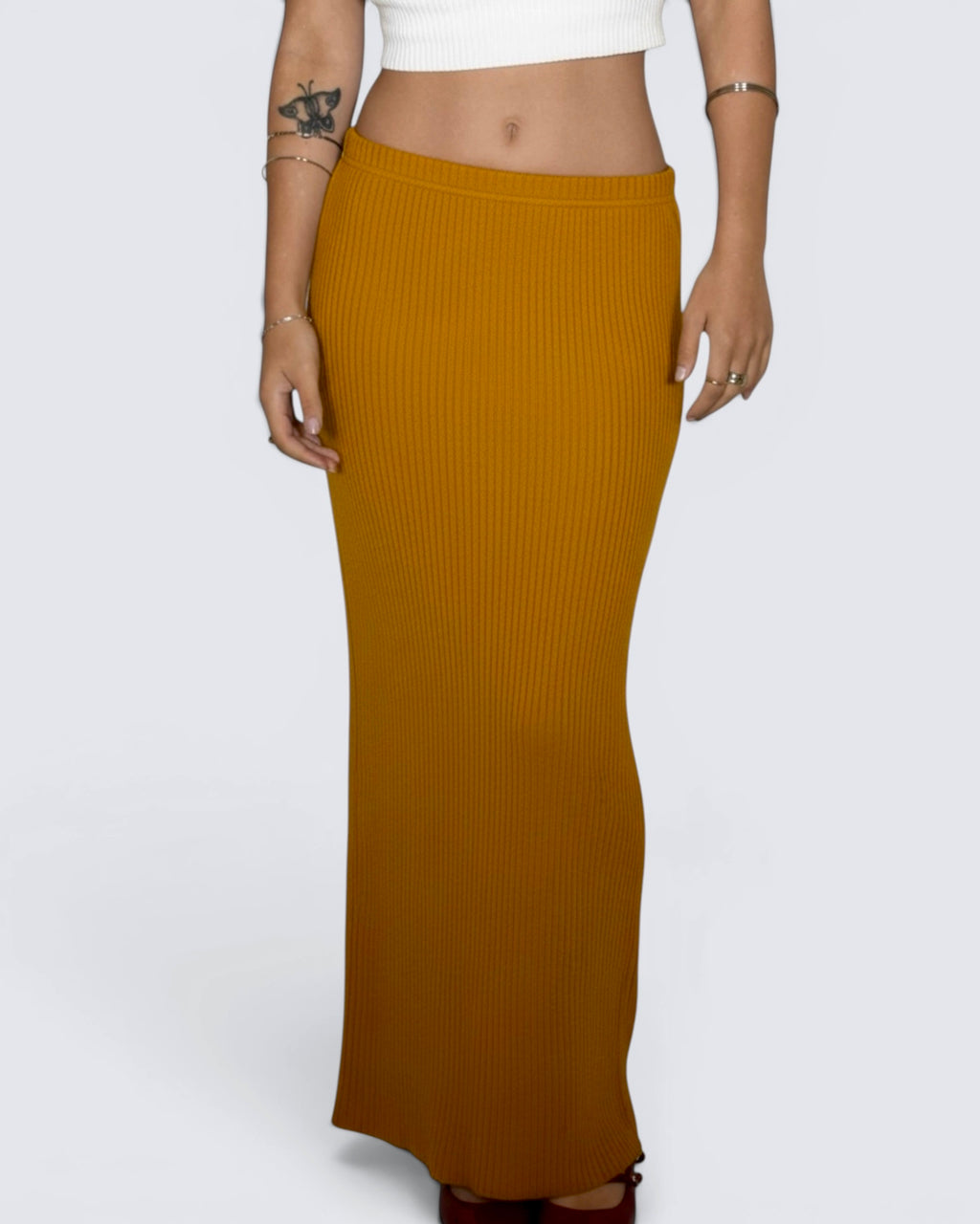 Mustard yellow ribbed skirt worn by a person on a white background