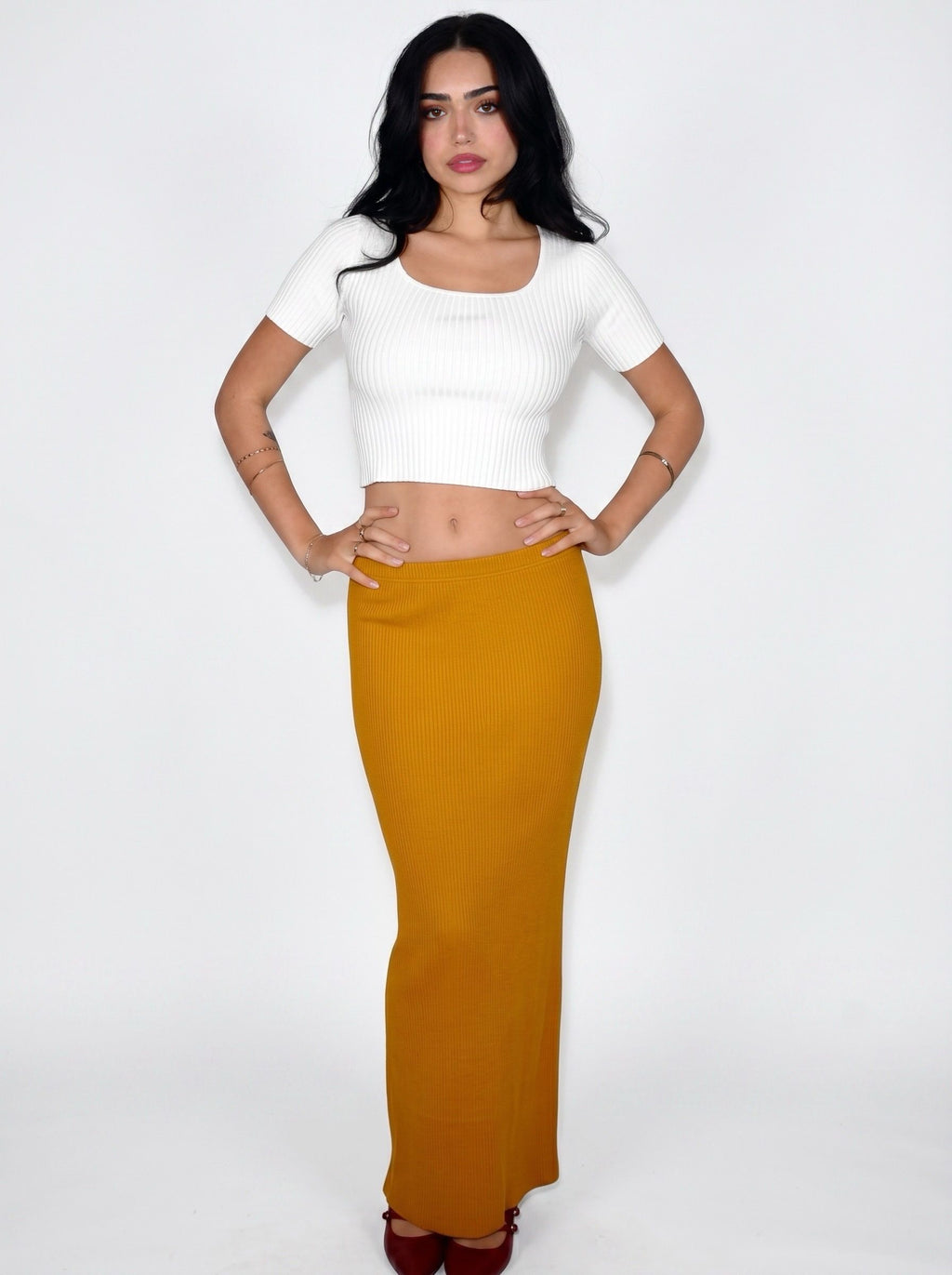 Woman wearing white rib knit crop top and mustard long straight skirt by TKHLA 