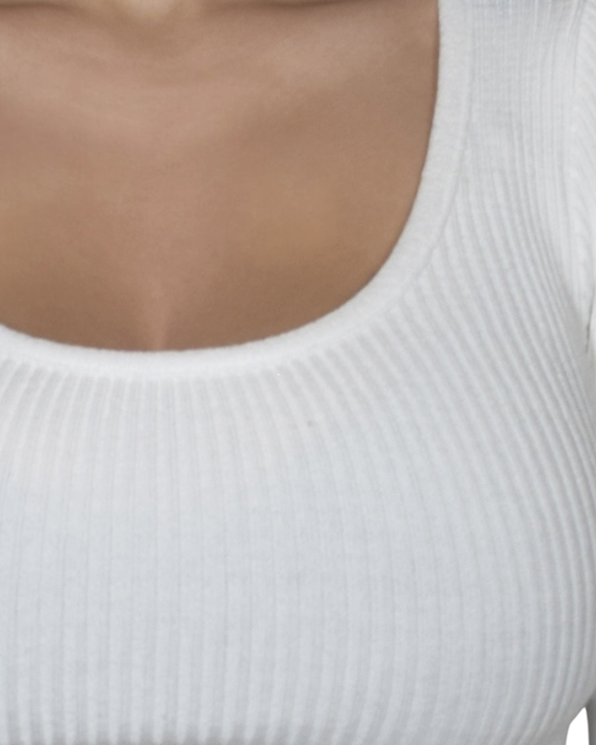 Close-up of a person wearing a white ribbed scoop-neck top.