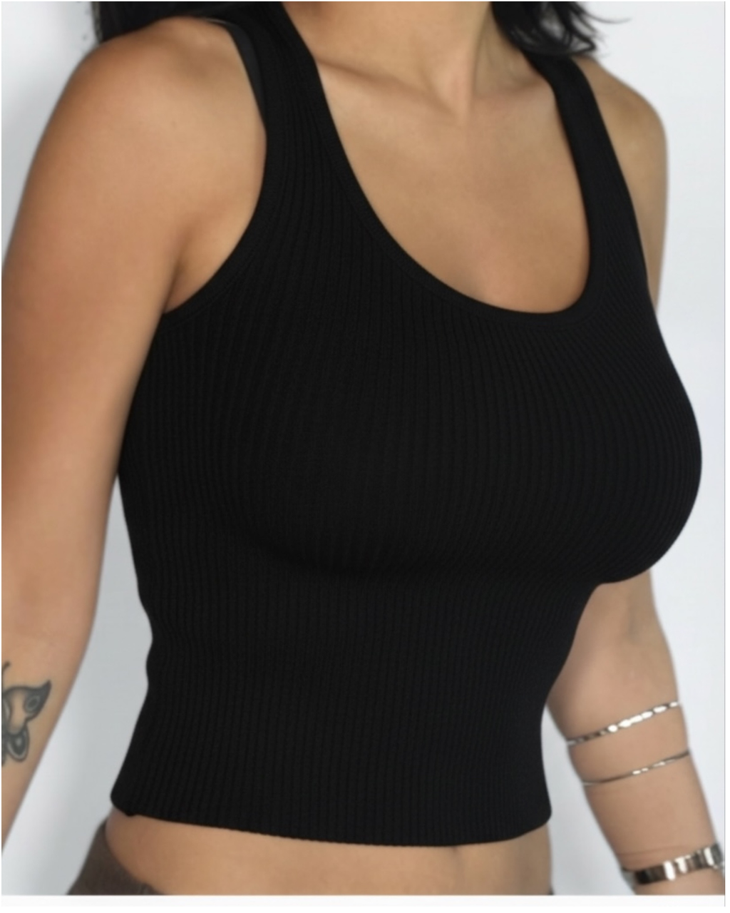 Black ribbed scoop-neck tank top worn by a person on a white background