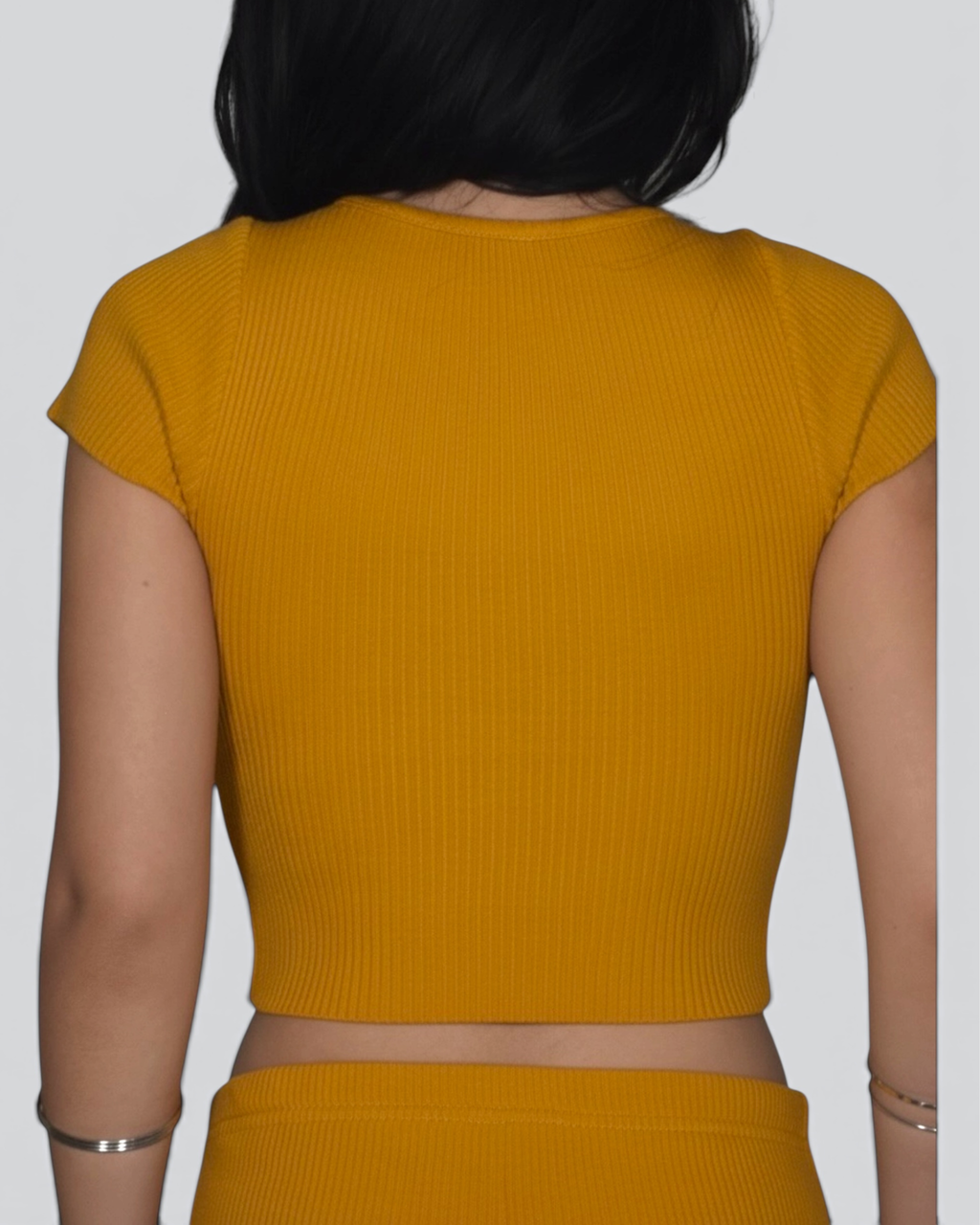Mustard yellow ribbed crop top worn by a person on a plain background