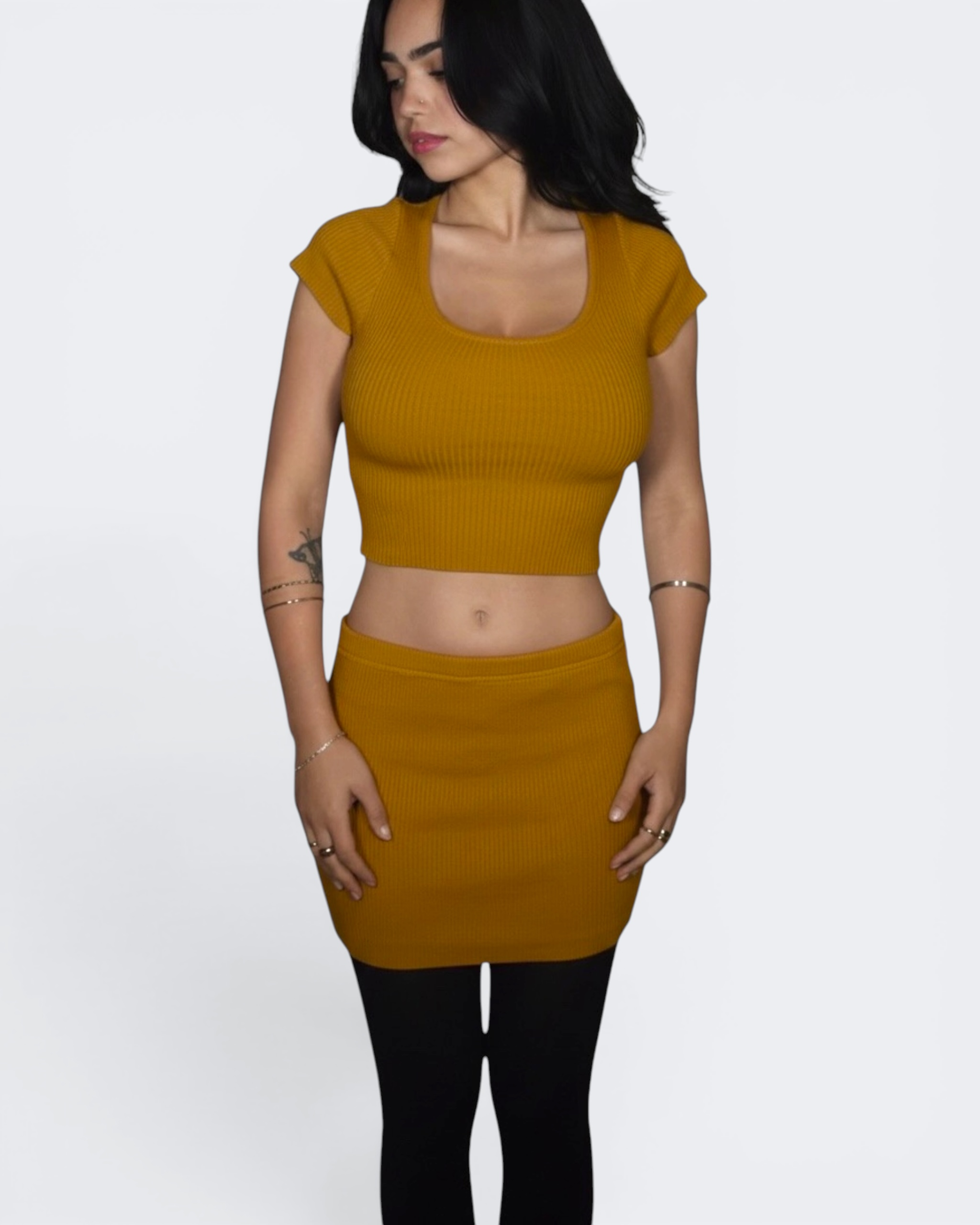 Woman wearing a mustard yellow top and skirt on a white background
