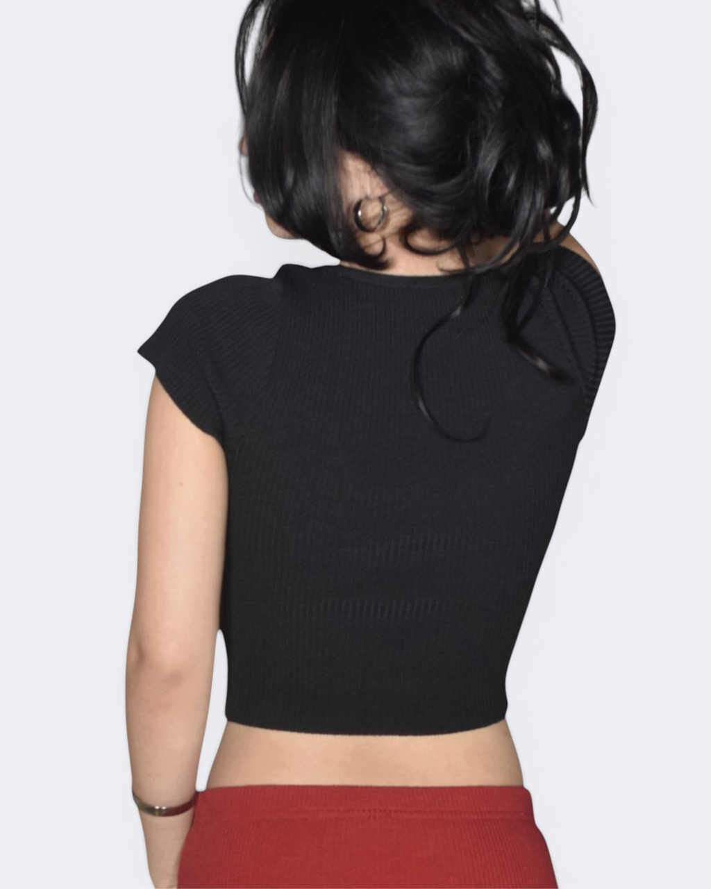 Person wearing a black crop top with a plain background