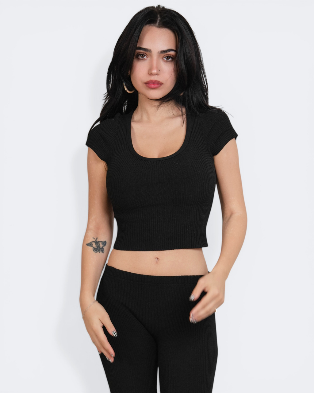 Woman wearing a black crop top and leggings on a white background