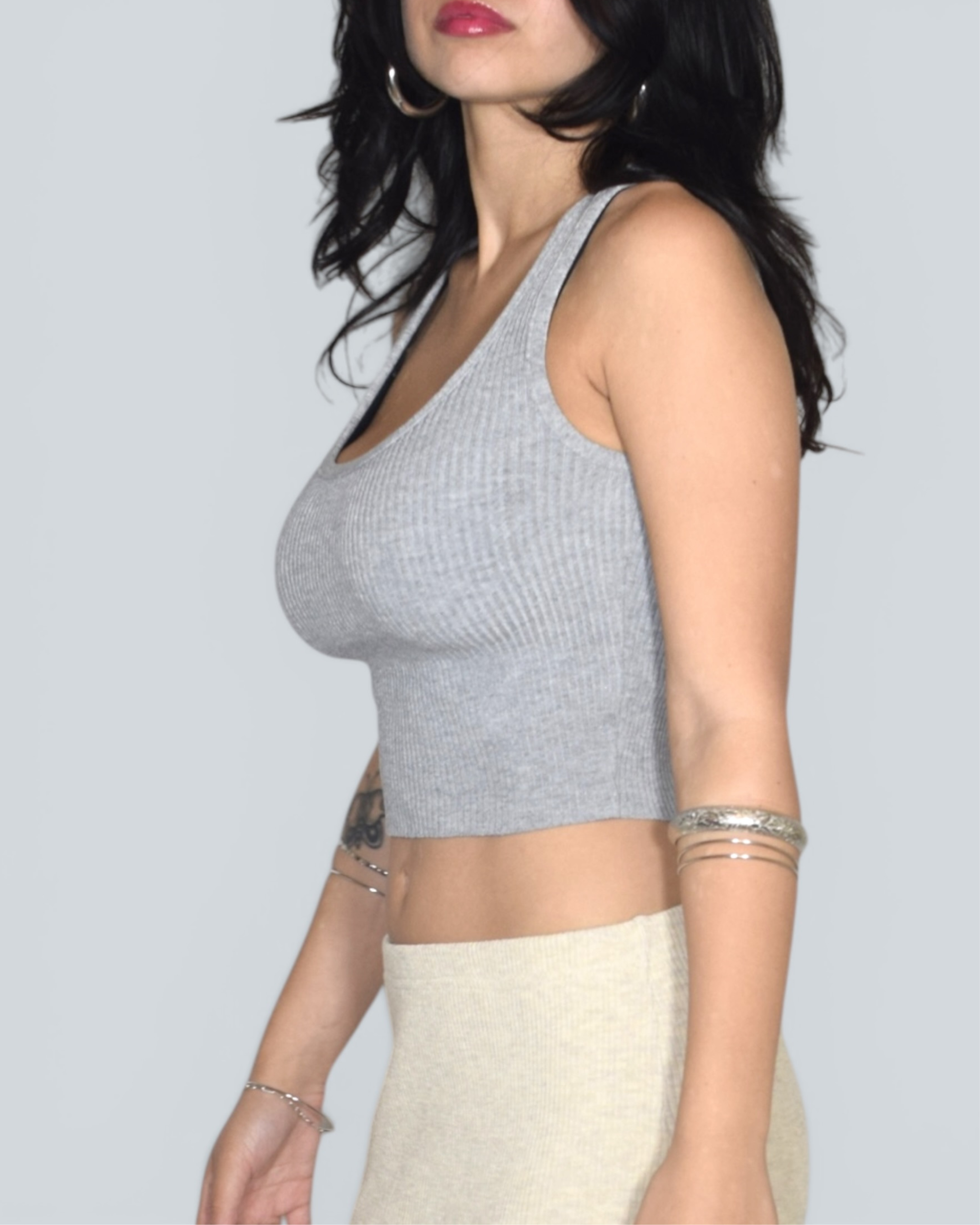 Woman wearing a gray ribbed tank top against a plain background