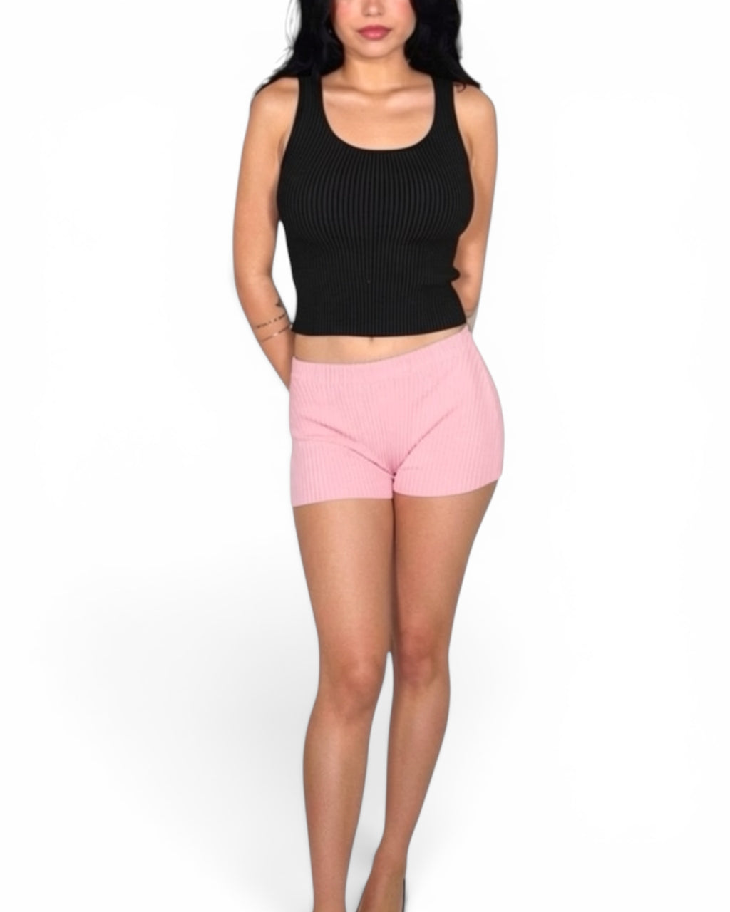 Person wearing a black crop top and pink shorts on a white background