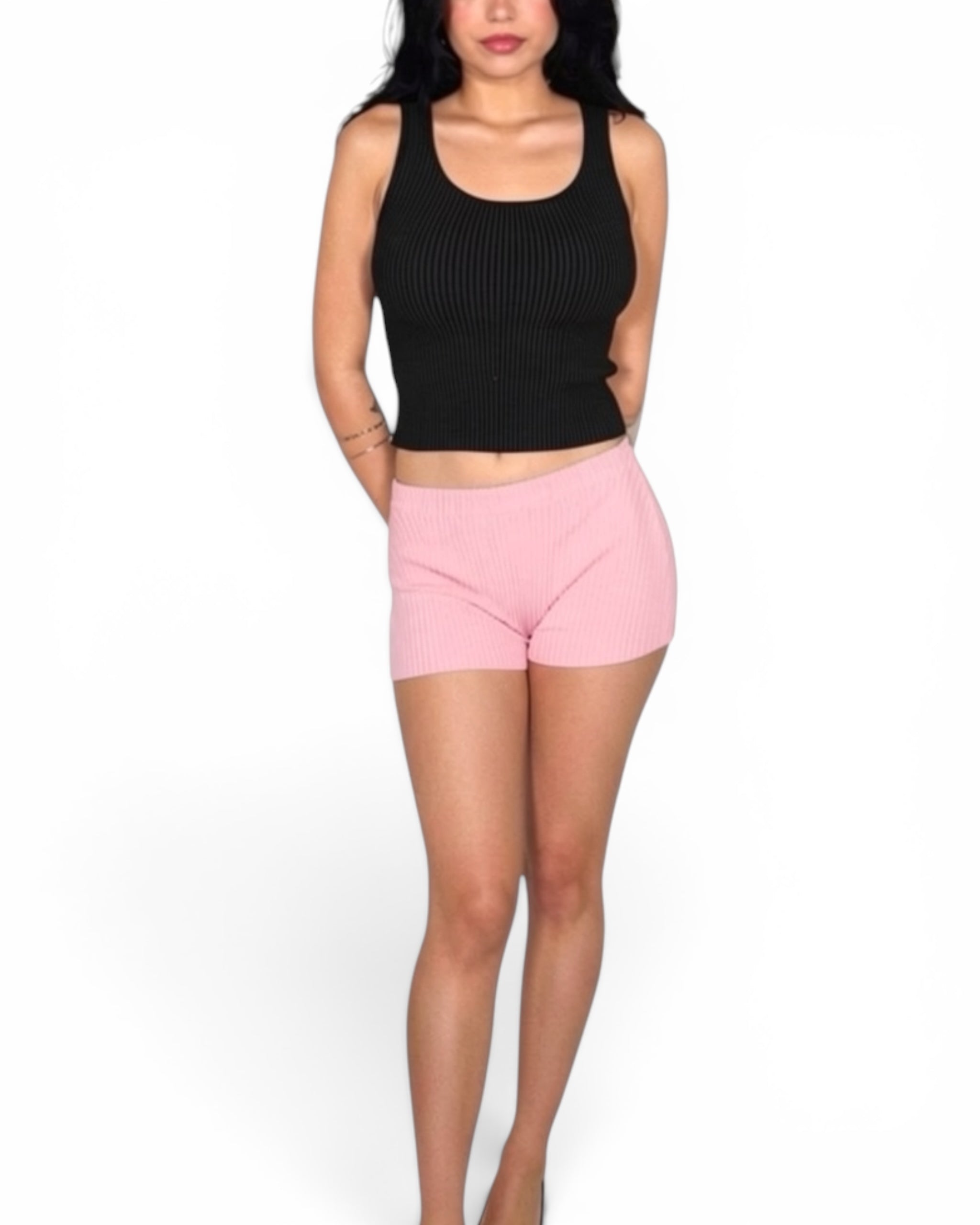 Person wearing a black crop top and pink shorts on a white background