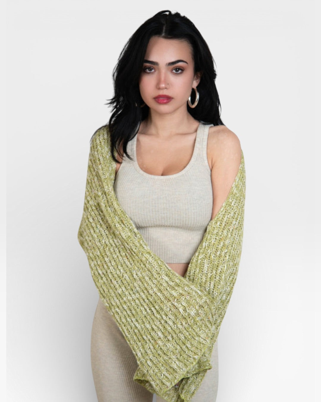 Woman wearing a dill green knitted shrug over ribbed knit tank top with scoop neckline in Drift beige by The Knit House LA  against a white background