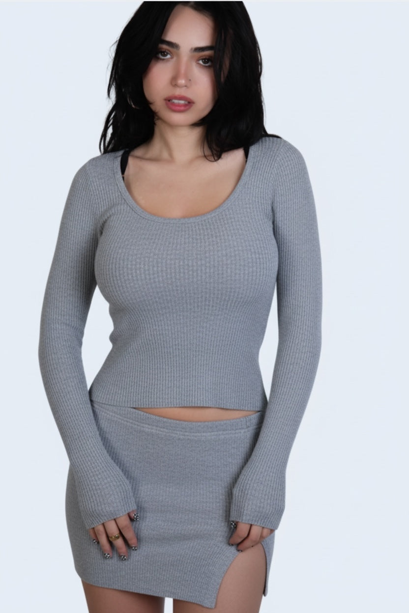 Woman wearing a gray long-sleeve top and skirt set on a white background