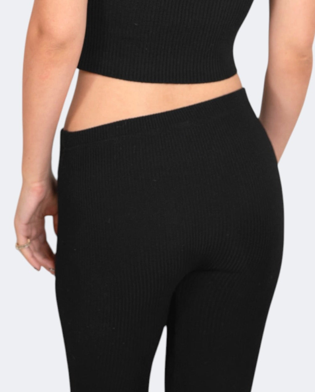 Person wearing a black crop top and leggings on a white background