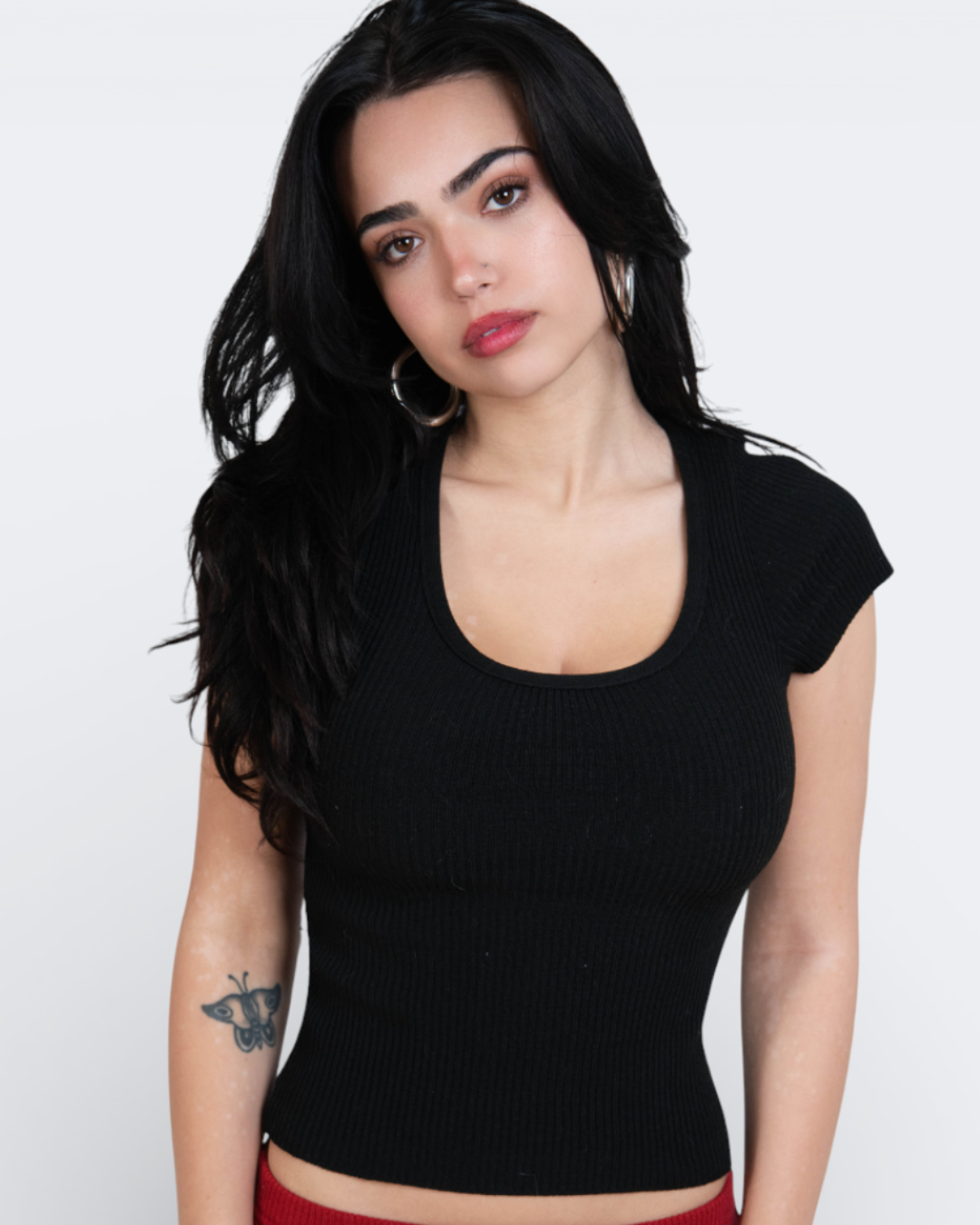 Woman wearing a black top and red pants on a white background