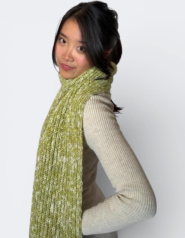 Woman wearing a green dill and bone knitted scarf by The Knit House LAagainst a white background