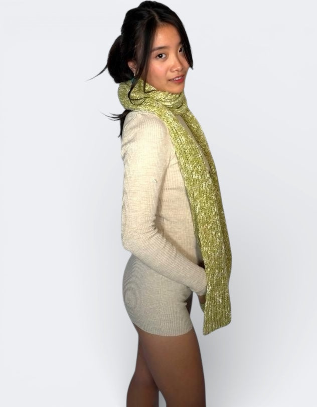Woman wearing a green dill and bone scarf by the Knit House LA and beige sweater on a white background