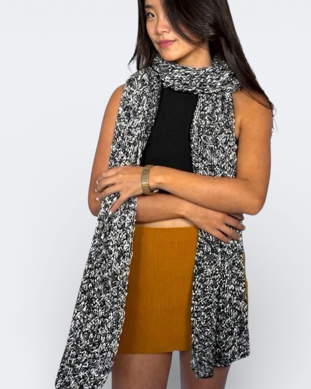 Woman wearing a black and white patterned scarf by The Knit House LA, with a plain background