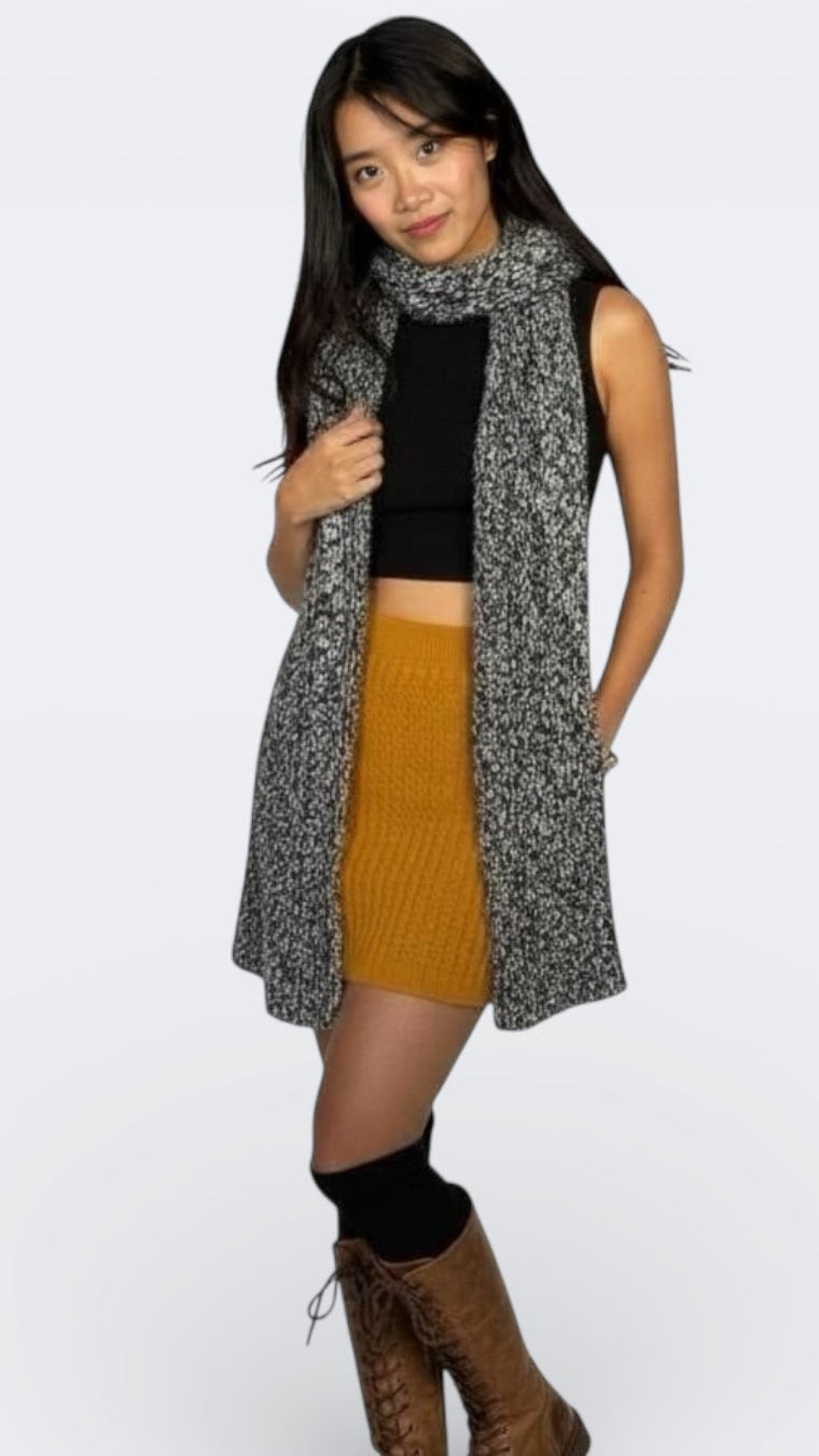 Woman wearing a patterned scarf in black and white, black top, mustard skirt, by The Knit House LA, on a white background