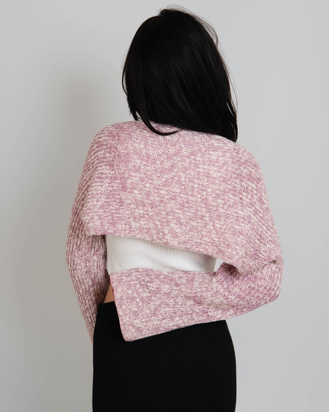 Back view of Woman wearing a pink and white mixed knit long sleeve shrug over a white scoop neck tank by The Knit House LA.