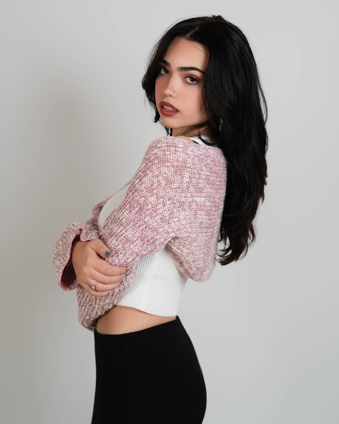 side view of Woman wearing a pink and white mixed knit long sleeve shrug over a white scoop neck tank by The Knit House LA.