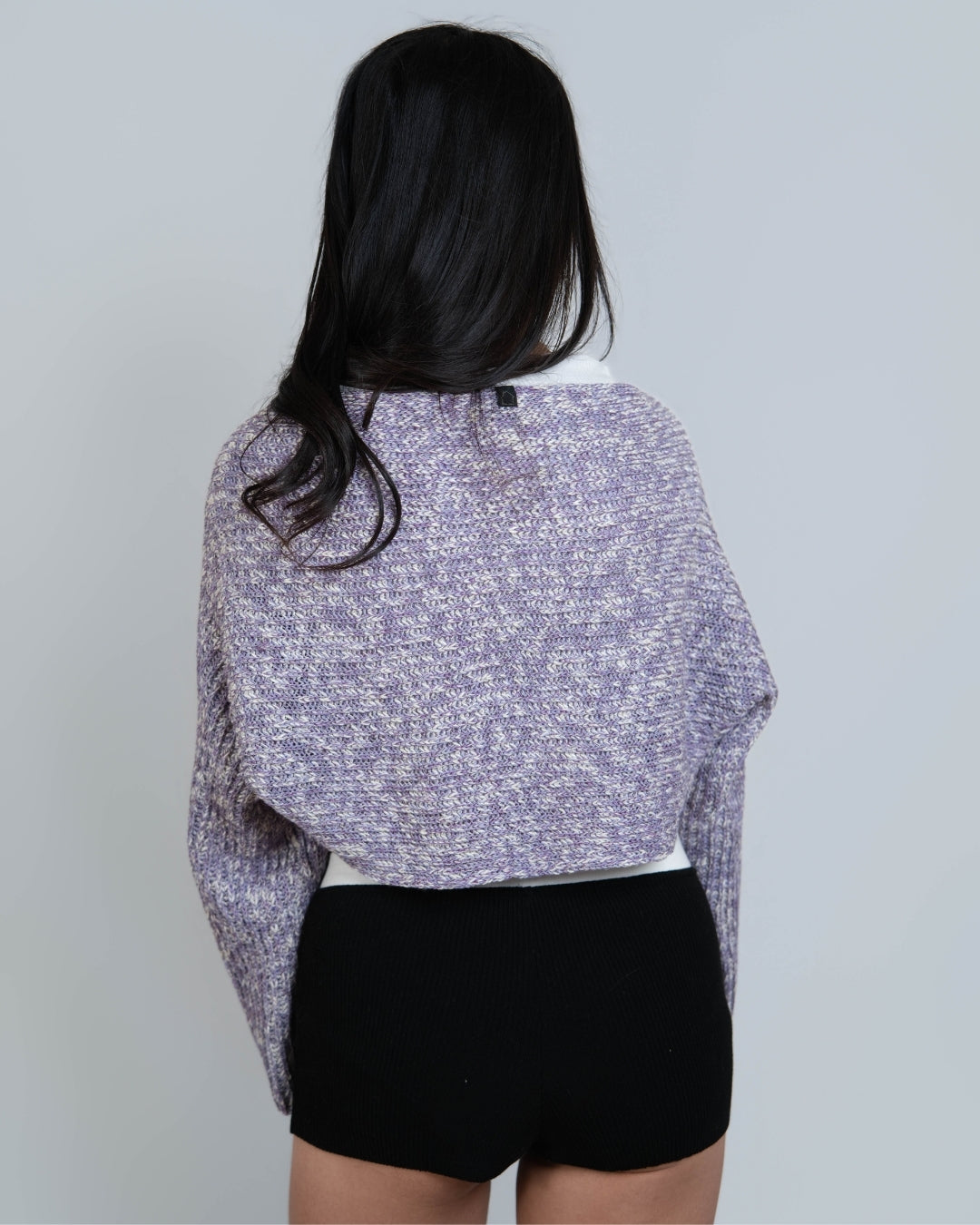 Woman wearing a long sleeve crop knit shrug in Violet purple and bone mixed knit by The Knit House LA.
