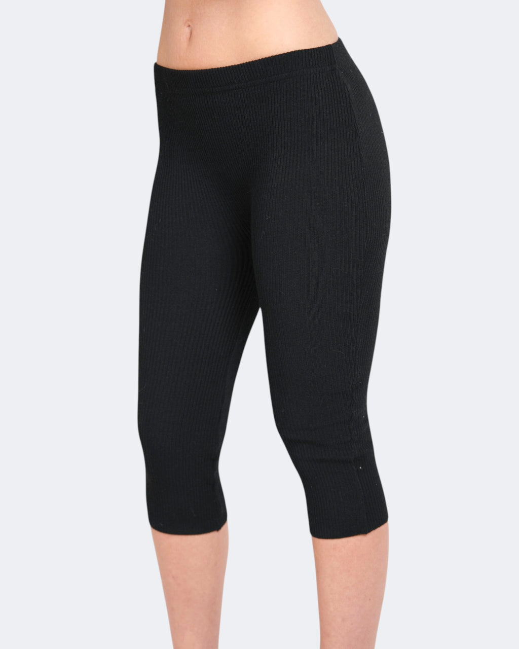 Black capri leggings worn by a person on a light gray background