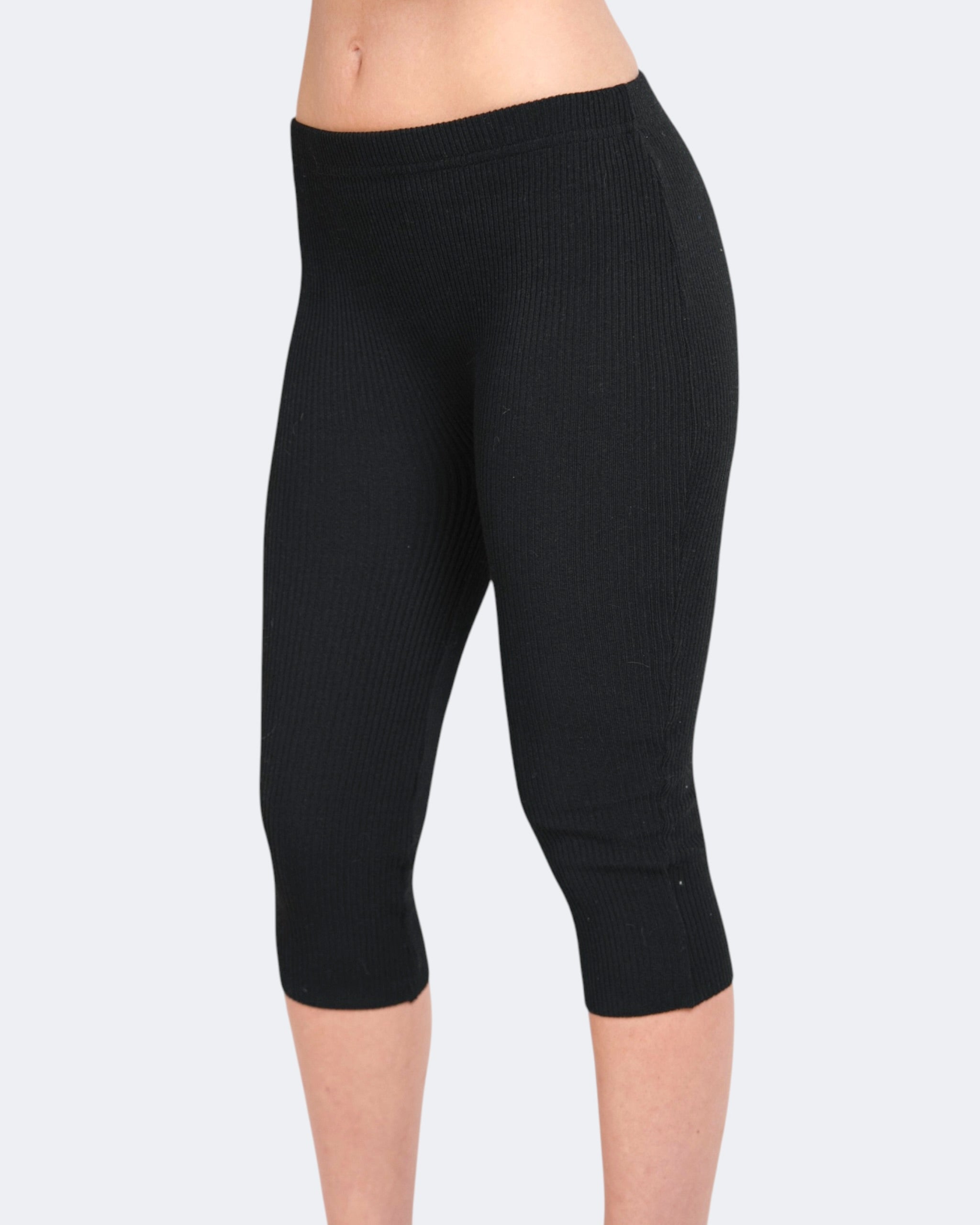 Black capri leggings worn by a person on a light gray background
