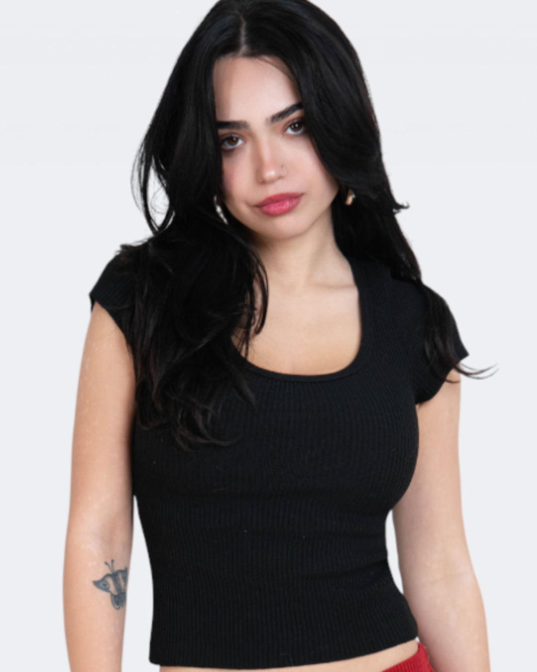 Woman wearing a black crop top and red capri pants on a white background