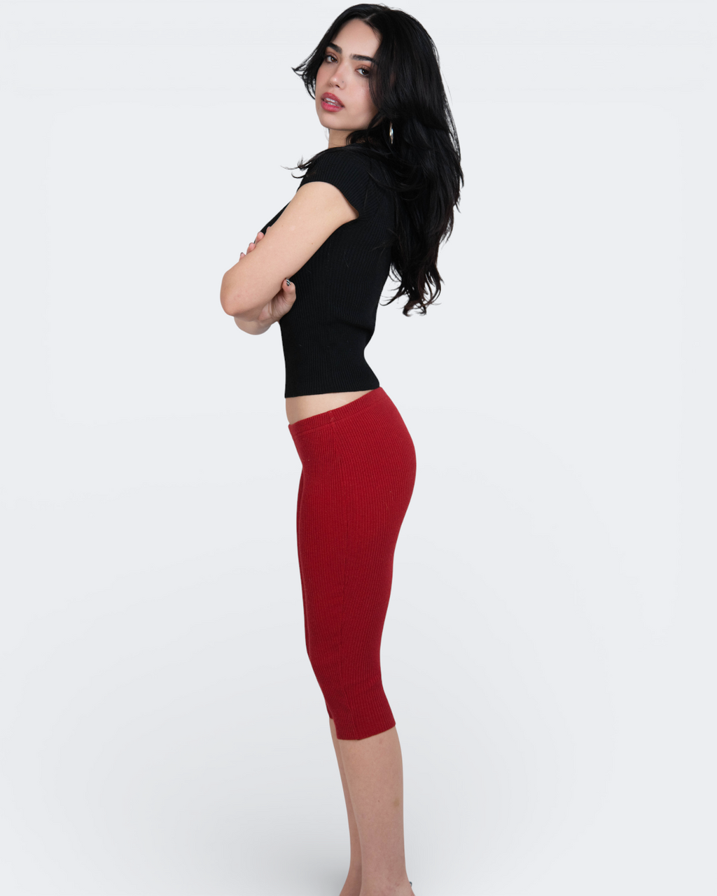 Woman wearing a black top and red capri pants on a white background