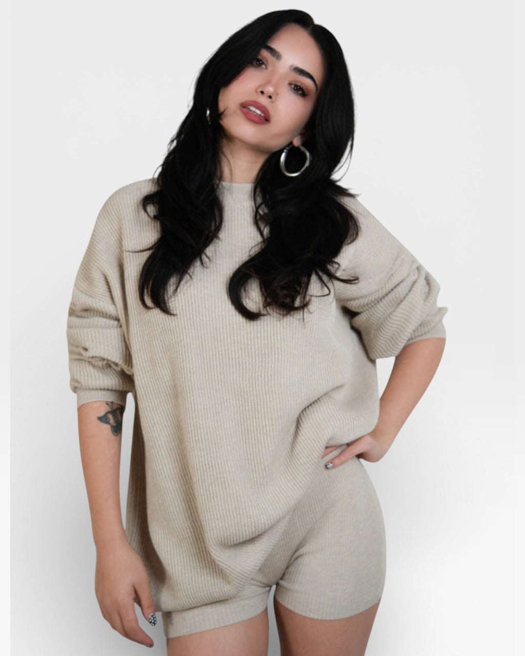 Woman wearing pair of fitted rib knit hot pant shorts in Drift beige by The Knit House LA.