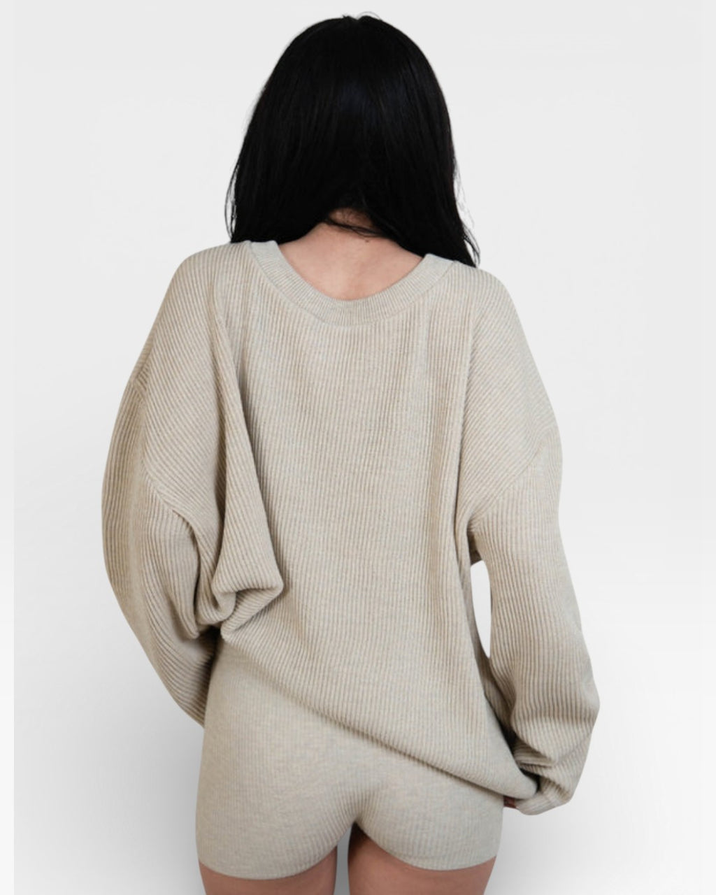 Woman wearing pair of fitted rib knit hot pant shorts in Drift beige by The Knit House LA.