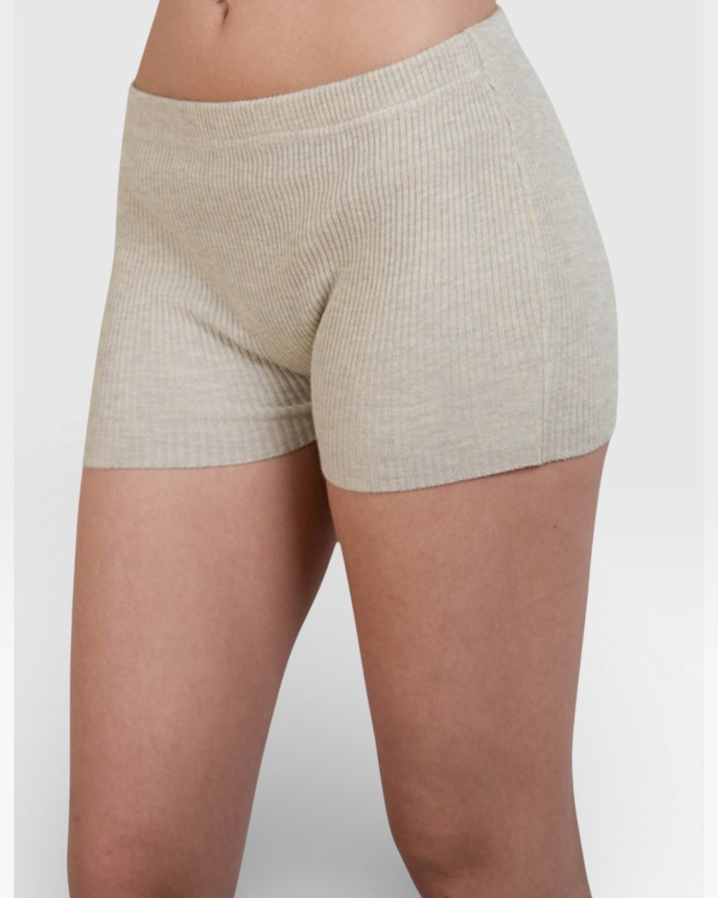 Woman wearing pair of fitted rib knit hot pant shorts in Drift beige by The Knit House LA.