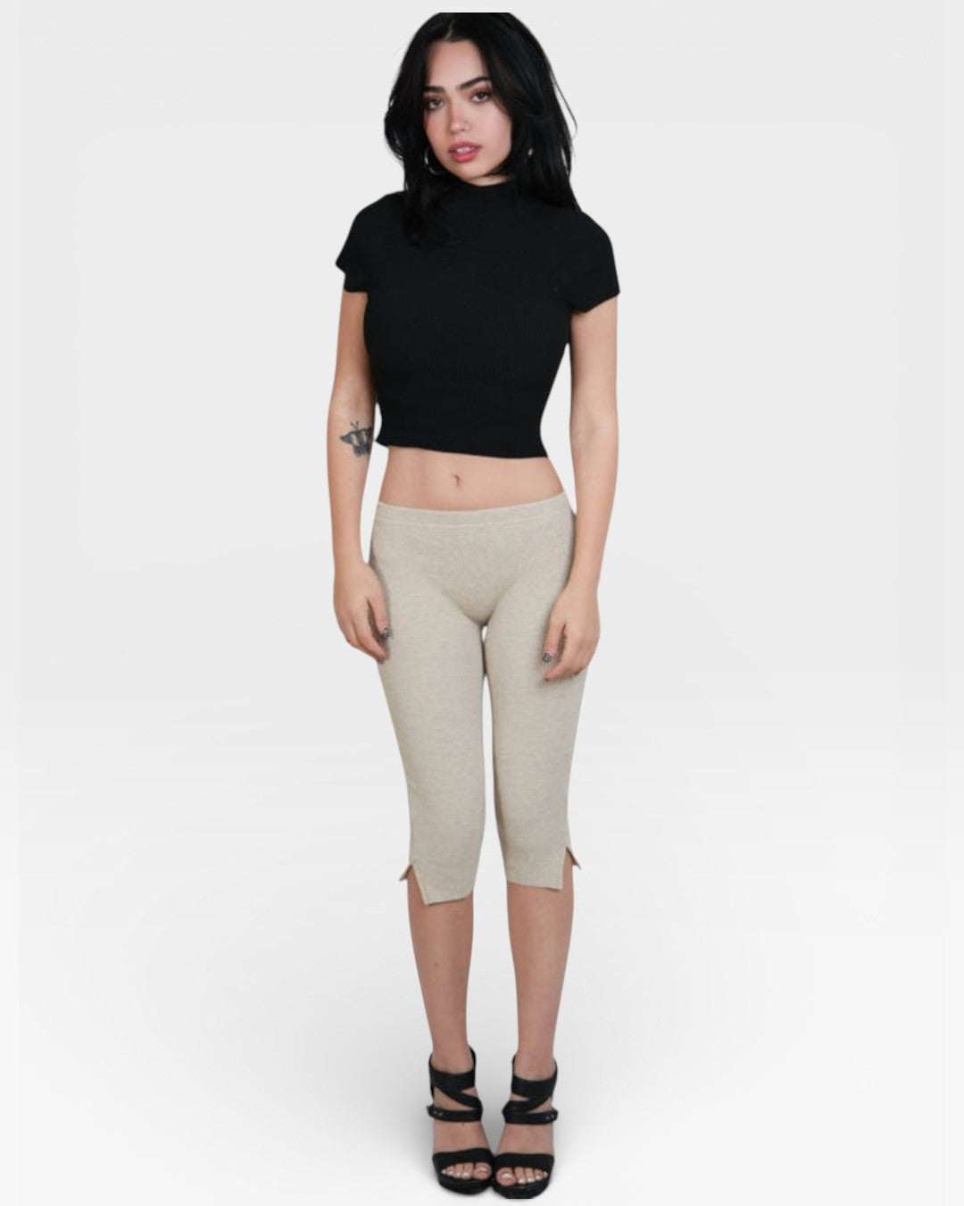 Woman wearing a black crop top and beige capri pants on a white background