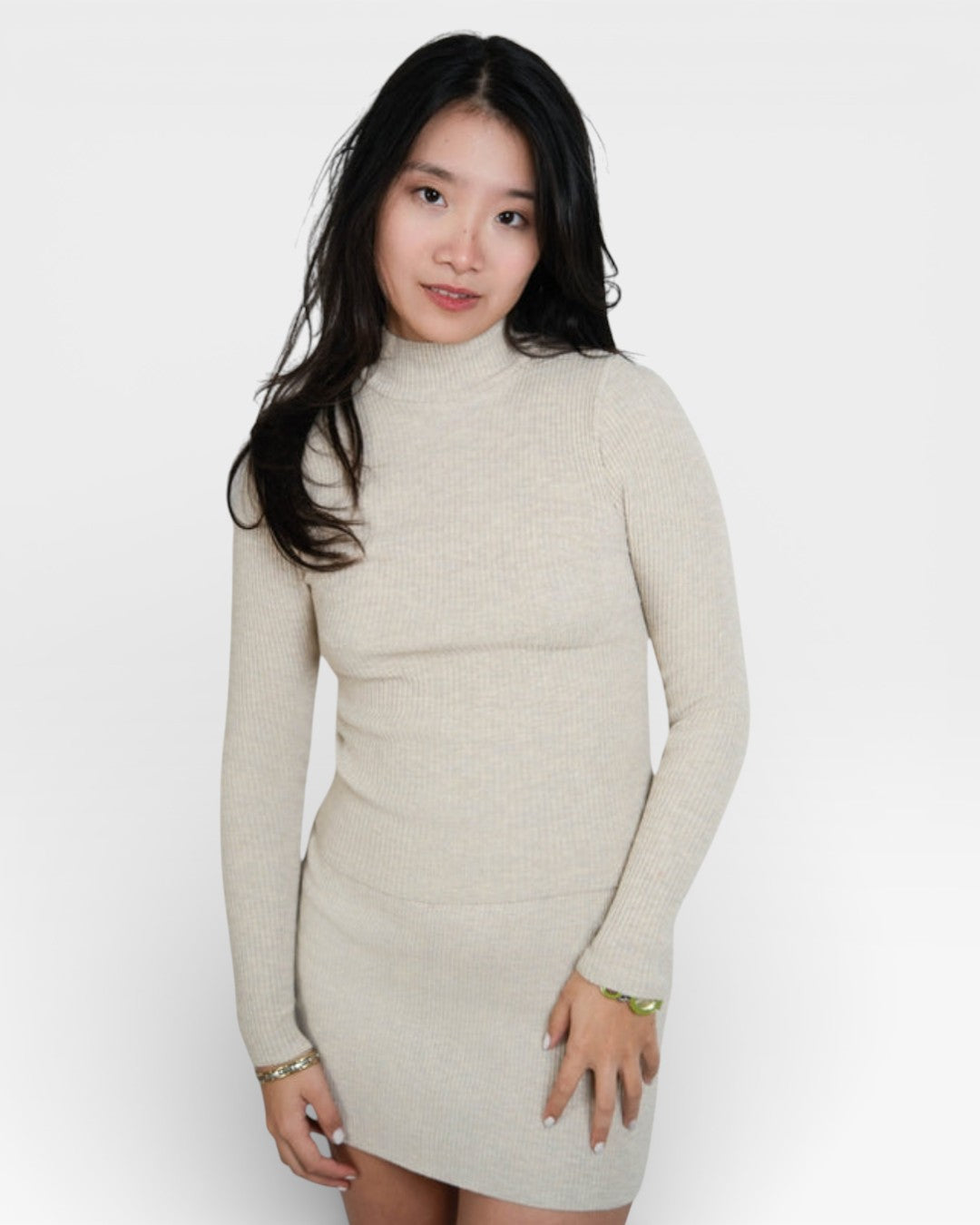 Woman wearing a beige long-sleeve dress against a white background