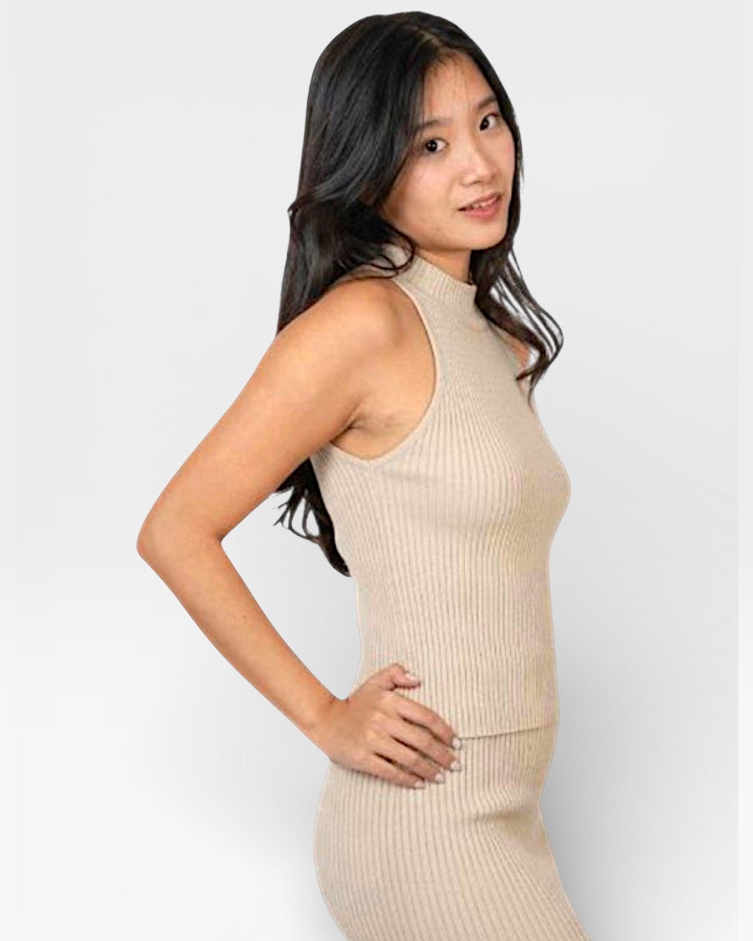 Side view of woman wearing a high necked fitted rib sleeveless knit shell in Drift beige by The Knit House LA.