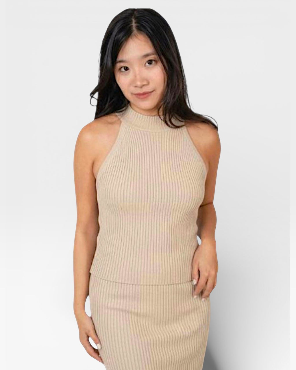 Woman wearing a high necked fitted rib sleeveless knit shell in Drift beige by The Knit House LA.