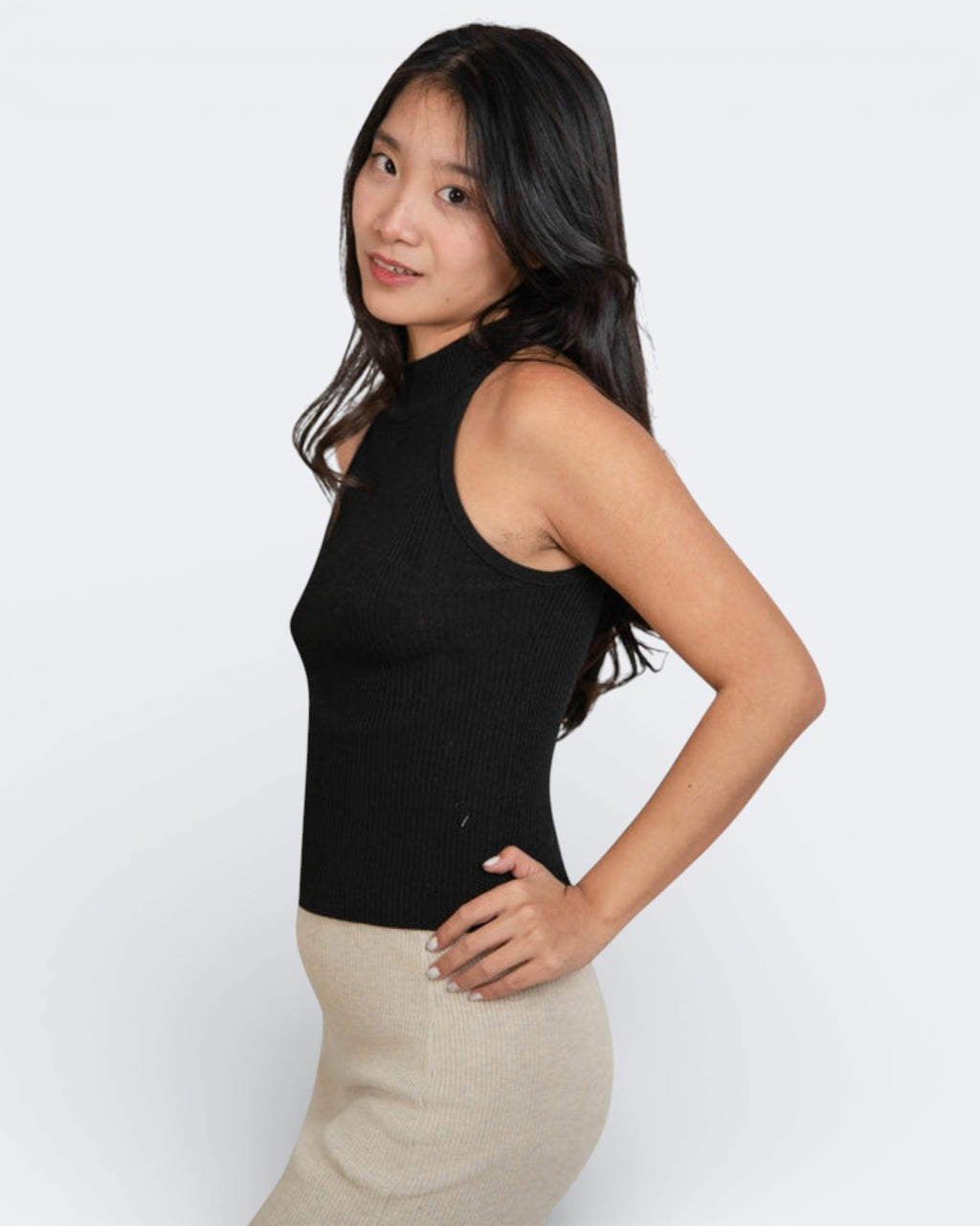 Side view of Woman wearing a fitted rib knit high neck sleeveless shell in Ink black by The Knit House LA.
