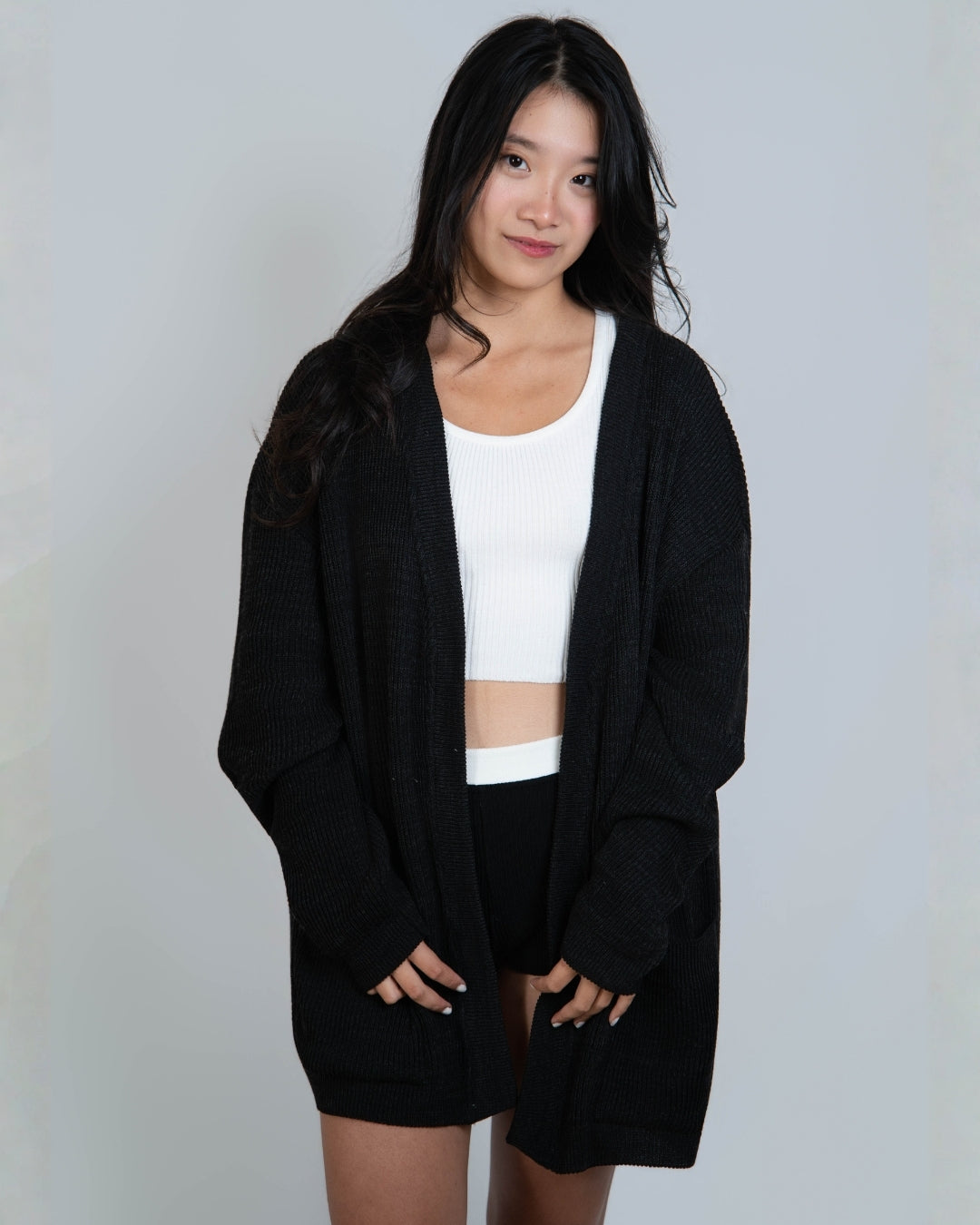 Woman wearing a relaxed oversized rib knit cardigan with generous patch pockets in Coal black by The Knit House LA.