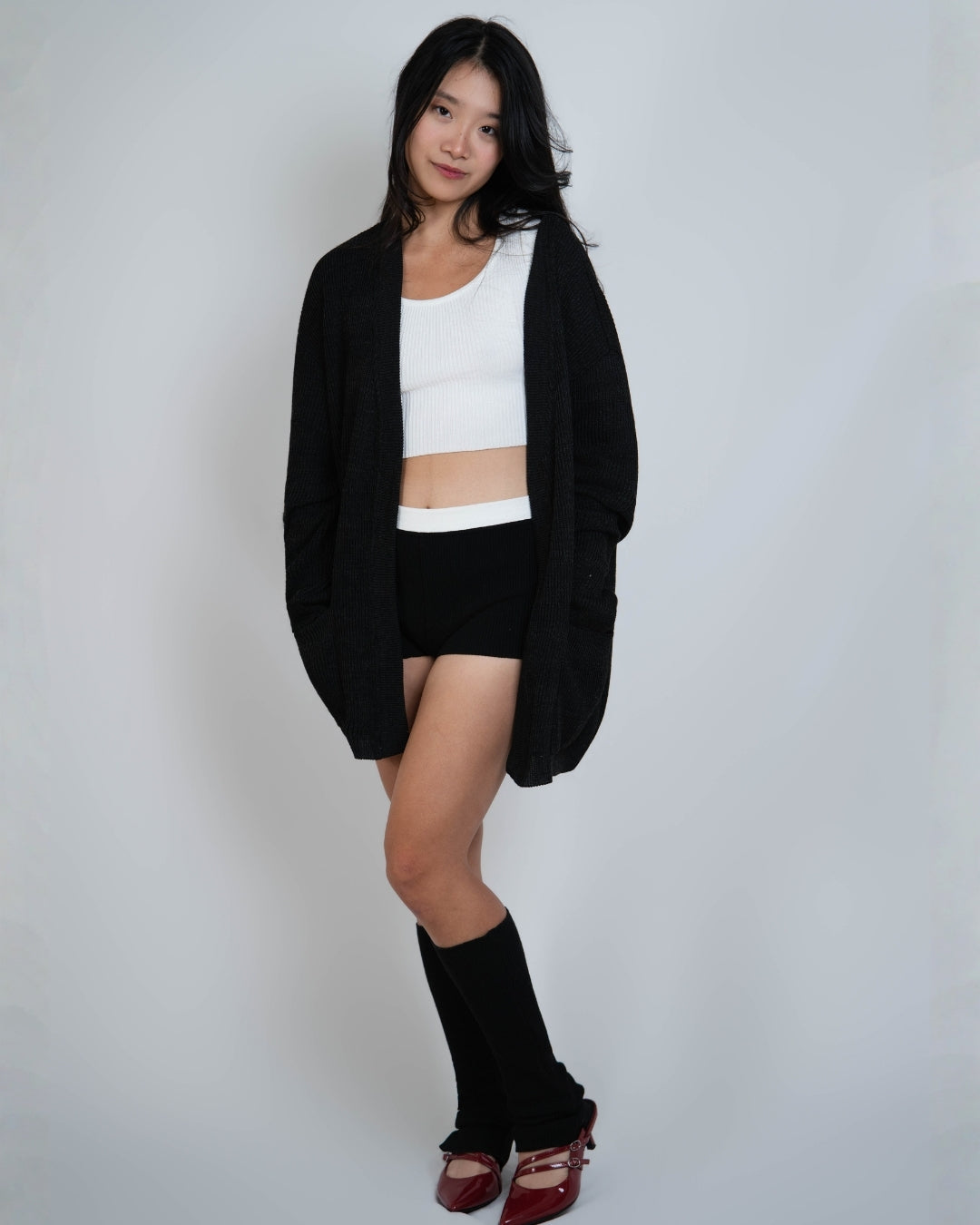 Woman wearing a relaxed oversized rib knit cardigan with generous patch pockets in Coal black by The Knit House LA.